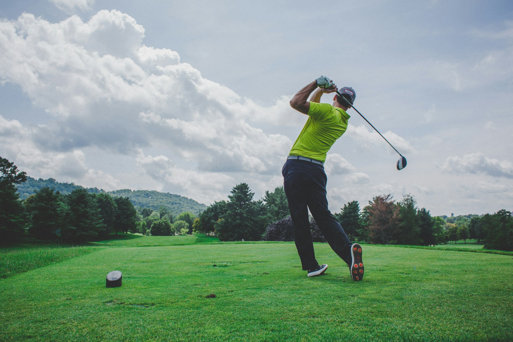 A golfer completing a swing during a round at a golf venue